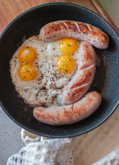 fried scrambled eggs with sausages in a frying pan