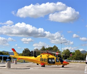 Fototapeta na wymiar The yellow helicopter landed in a parking area for the first aid mission.