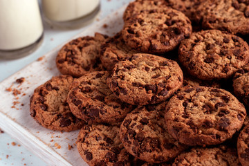 Chocolate chip cookies stacked on a wooden chopping board