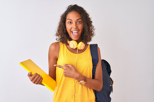 Brazilian student woman wearing backpack holding notebook over isolated white background very happy pointing with hand and finger