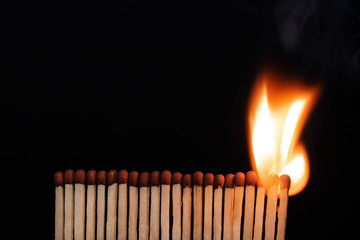 A row of burning matches on a black background. The flame moves from the match to the match. Fire is inevitable.