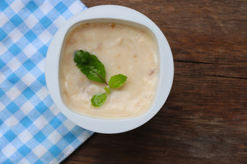 Prune yogurt with pepper mint topping good healthy and delicious in plastic glass on wood table background
