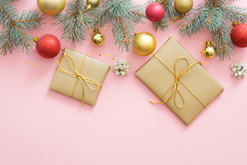 Christmas holiday composition. Xmas tree fir branches, colorful balls, gifts box on pastel pink background. Christmas, winter, New Year concept. Flat lay, top view, overhead.