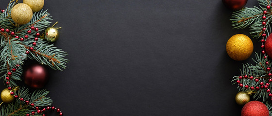 Christmas banner. Black Xmas background with fir tree branches, golden and red balls, garland....