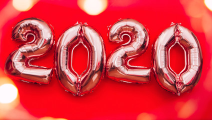 2020 happy new year in the form of silver balls on a red background. gel balls in the form of numbers 2020. Christmas atmosphere card. Bokeh from a garland of light bulbs on a red background.