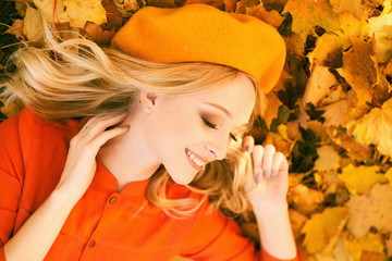 Girl lying on fallen leaves of maple tree autumn