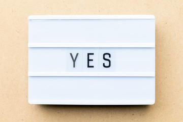White lightbox with word yes on wood background
