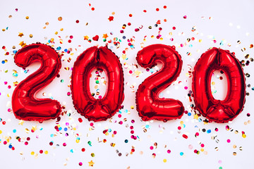 2020 happy new year in the form of red balloons isolated on white background. scattered confetti on a white background. Christmas card. gel balls in the form of numbers 2020. holiday atmosphere.