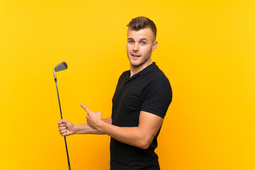 Golfer player man over isolated yellow background and pointing it