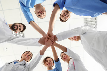 Fototapeta na wymiar Team of medical workers holding hands together in hospital, bottom view. Unity concept