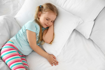 Portrait of cute little girl sleeping in large bed, above view