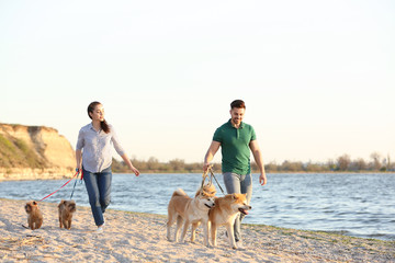 Young couple walking their adorable dogs near river
