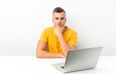 Young blonde man in a table with a laptop laughing