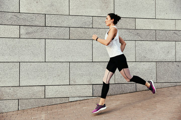 Fototapeta premium Beautiful sporty young woman running on street, space for text