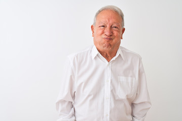 Senior grey-haired man wearing elegant shirt standing over isolated white background puffing cheeks with funny face. Mouth inflated with air, crazy expression.