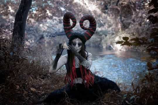Fairytale photo with demonic horned faun playing on the jawbone of an animal