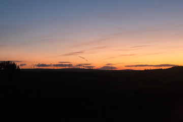 Orange sunset in late summer in Ireland wind turbines visible on horizon 