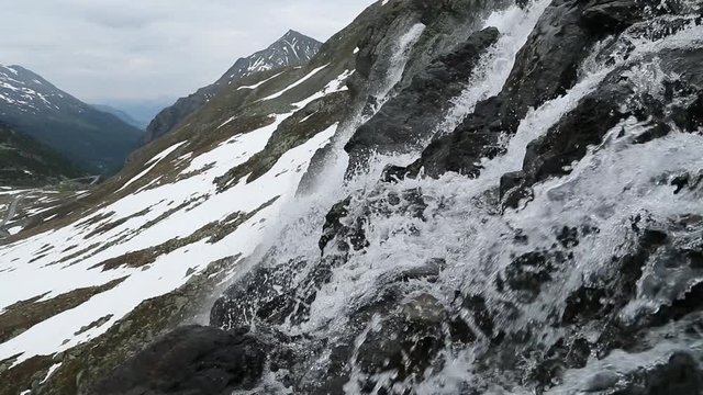 Beautiful waterfal near the Susch pass near Davos in Swizerland surrounded by snow. Filmed in slowmotion in June.