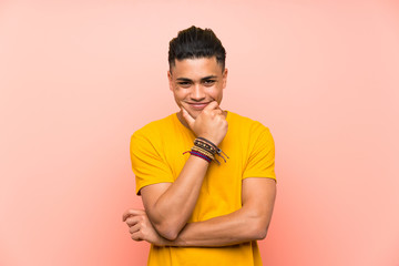Young man with yellow shirt over isolated pink wall laughing