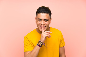 Young man with yellow shirt over isolated pink wall doing silence gesture