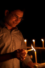 Background Photo For Diwali. Indian Man lighting up candles at night on Diwali kali puja or pooja -...