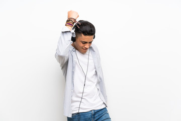 Young man over isolated white wall with earphones