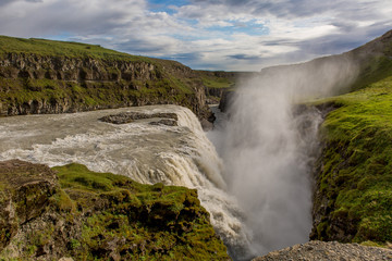 Fototapeta premium Gorge in the mountains with a waterfall. Around the green grass