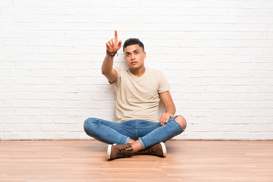 Young man sitting on the floor touching on transparent screen