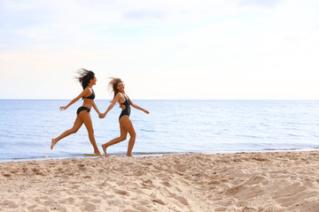 Fototapeta na wymiar Young woman in bikini with girlfriend on beach. Lovely couple