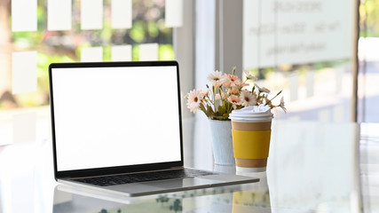 Laptop computer, take away coffee and flower on table.