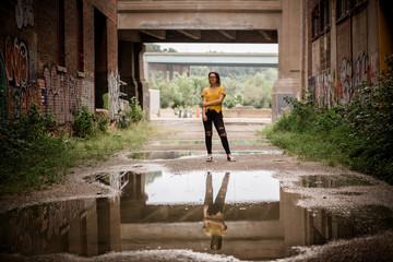 Teenager girl standing in front of water puddle in urban area. 