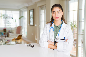 Young doctor woman wearing medical coat at the clinic skeptic and nervous, disapproving expression on face with crossed arms. Negative person.