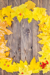 Yellow and orange fallen maple leaves on dark brown wood table background.