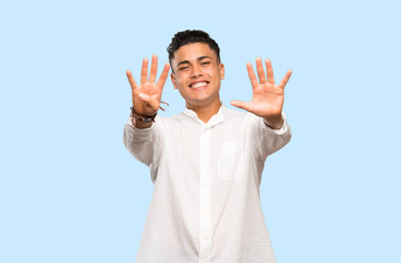 Young man counting nine with fingers on colorful background