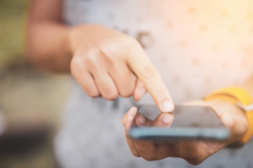 Close up woman hand hold using smart phone on outdoor park street background.