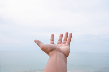 Man open hand raise up on sky background at beach. Freedom feel good concept.