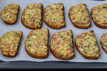 Homemade hot sandwiches with cheese and sausage, on parchment on a baking tray, horizontal orientation