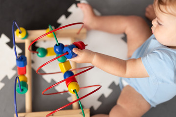 Baby playing with educational toy in nursery. Learning colorful wooden toy.developing toy. The labyrinth of wooden beads.geometric toy, counting, feeling. Bead roller coaster toys. Childhood.