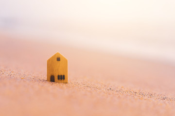 Small home model on sunset beach sand texture background.