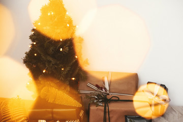Merry Christmas. Stylish gift boxes under Christmas tree with festive golden lights in white room.  Winter holidays preparation. Happy Holidays .Copy space. Season's Greeting
