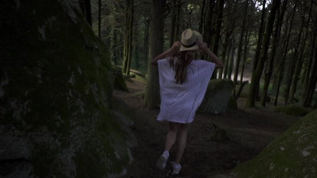 Beautiful young woman running in wonderful magic forest in Sintra. Fairytale mysterious landscape with tall green trees, plants and big stones.