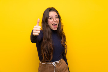 Teenager girl over isolated yellow wall with thumbs up because something good has happened