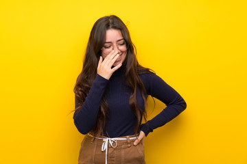 Teenager girl over isolated yellow wall smiling a lot