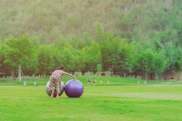 Happiness girl in the floral skirt relax and play with a big ball on green field in the public...