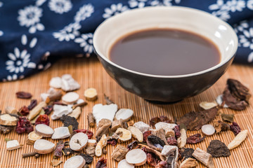 All kinds of traditional Chinese medicine and a bowl of traditional Chinese medicine soup scattered on the bamboo mat