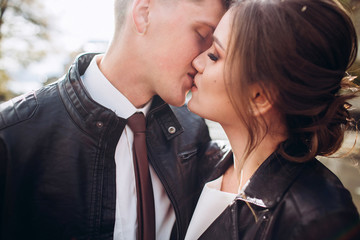 A young couple on a sunny autumn day walk around the city. Couple in love. Emotions Portrait of a happy husband and wife on a background of greenery. funny guy and girl laugh outdoors in the rain.
