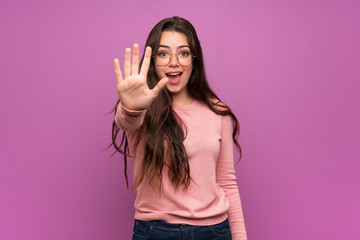 Teenager girl over purple wall counting five with fingers