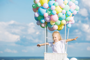 Little cute child girl beautiful and happy on green grass with balloon airship on blue sky background with clouds