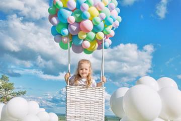 Little cute child girl beautiful and happy on green grass with balloon airship on blue sky background with clouds