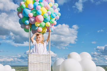Little cute child girl beautiful and happy on green grass with balloon airship on blue sky background with clouds